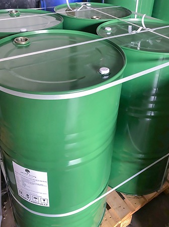 Four green steel drums containing bulk extra virgin olive oil from Artem Oliva, secured together and placed on a pallet for shipping.